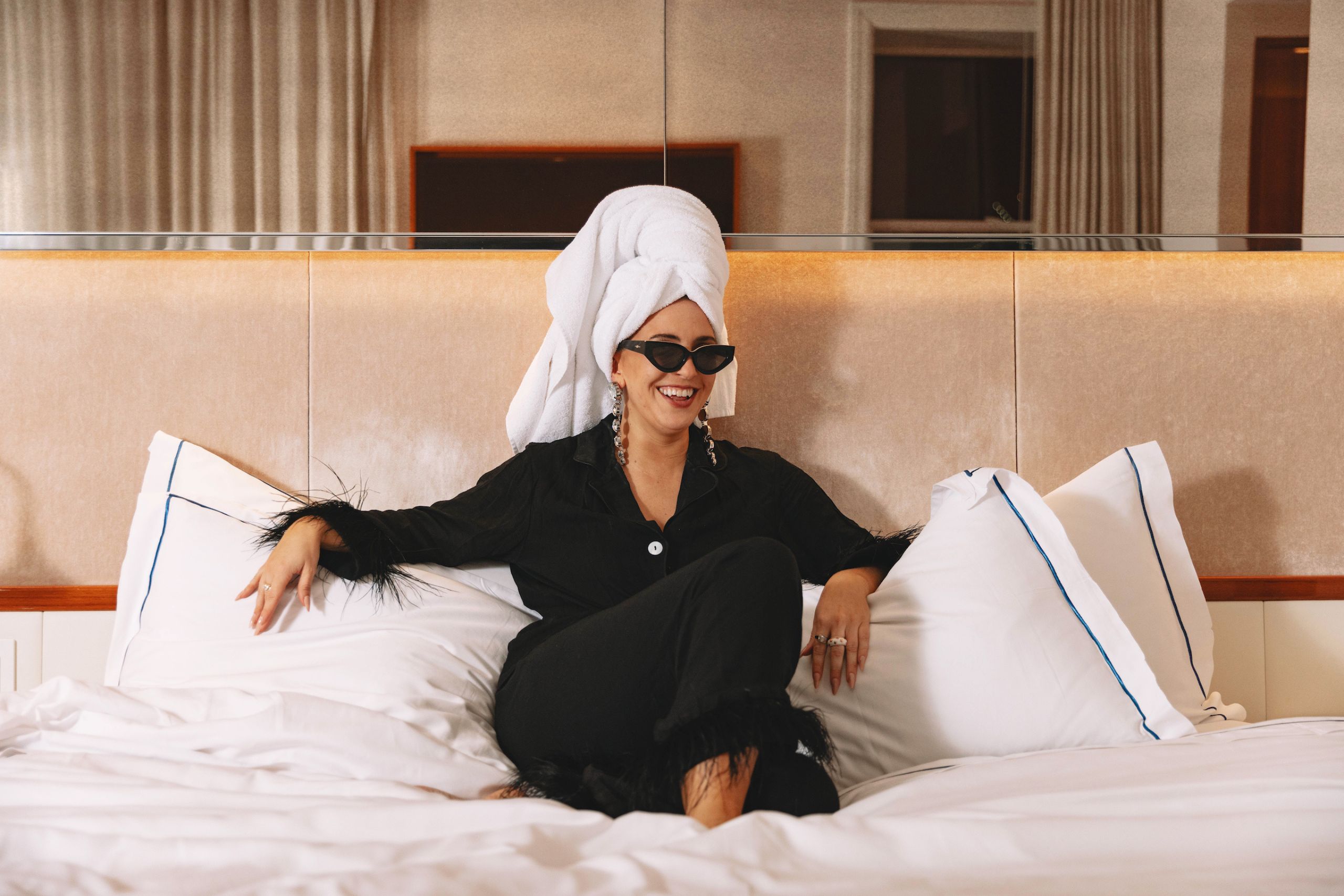 woman in black pajamas and towel on head sitting on bed
