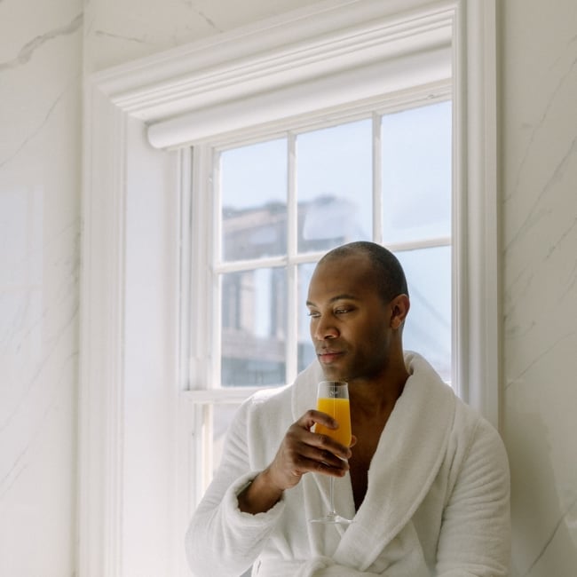 man in a robe drinking orange juice