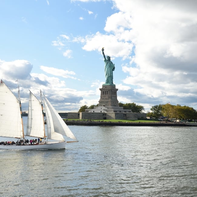 sail boat with the statue of liberty in the background